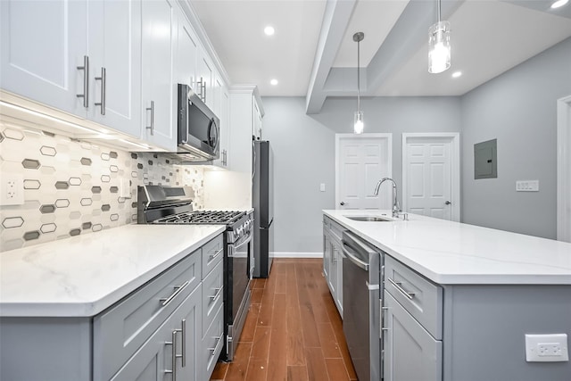 kitchen featuring dark wood finished floors, gray cabinetry, appliances with stainless steel finishes, a sink, and an island with sink