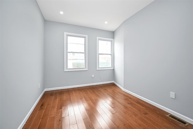 unfurnished room featuring recessed lighting, wood-type flooring, visible vents, and baseboards