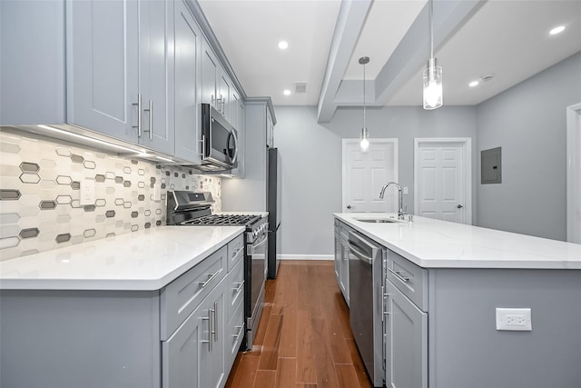 kitchen featuring dark wood-style floors, gray cabinets, backsplash, appliances with stainless steel finishes, and a sink