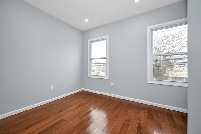 spare room with dark wood-type flooring, a wealth of natural light, and baseboards