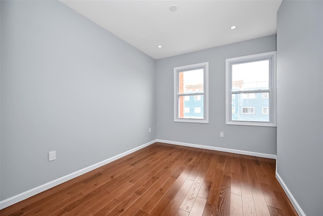 empty room featuring dark wood-style flooring, recessed lighting, and baseboards