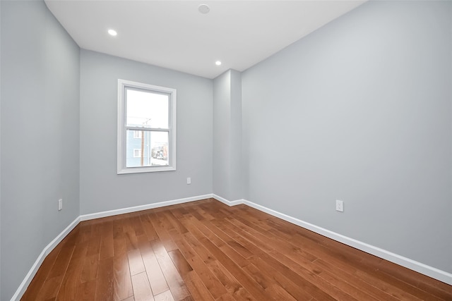 unfurnished room featuring recessed lighting, hardwood / wood-style flooring, and baseboards