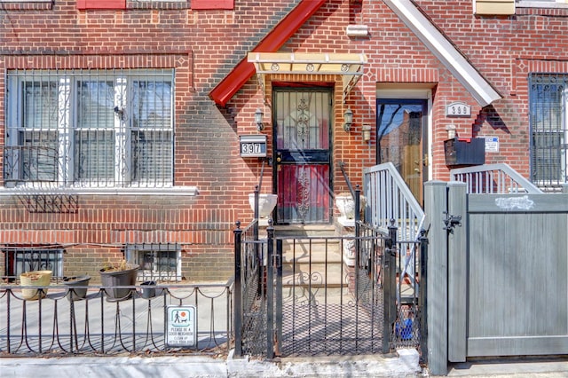 view of exterior entry with fence, brick siding, and a gate