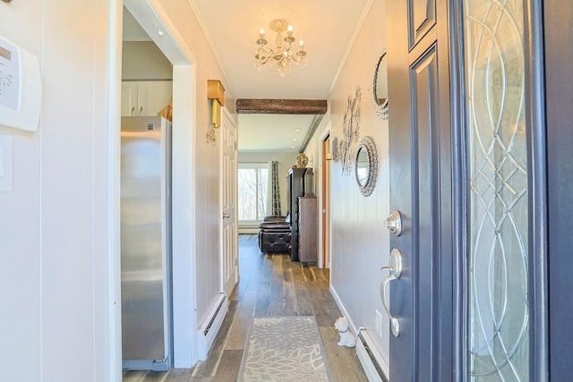 hall featuring baseboard heating, ornamental molding, an inviting chandelier, and wood finished floors