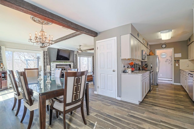 dining space featuring beamed ceiling, wood finished floors, a fireplace, and ceiling fan with notable chandelier