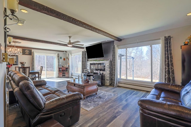 living area featuring wood finished floors, a baseboard radiator, beam ceiling, a glass covered fireplace, and ceiling fan with notable chandelier