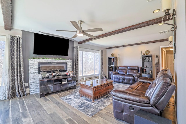 living room with a ceiling fan, beam ceiling, wood finished floors, and visible vents