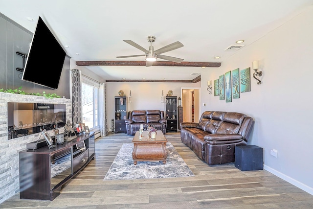 living area with visible vents, ceiling fan, baseboards, beamed ceiling, and wood finished floors