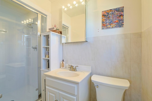 bathroom with a shower stall, vanity, tile walls, and toilet