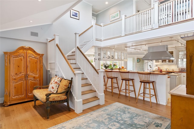 stairs with visible vents, crown molding, a high ceiling, and wood finished floors