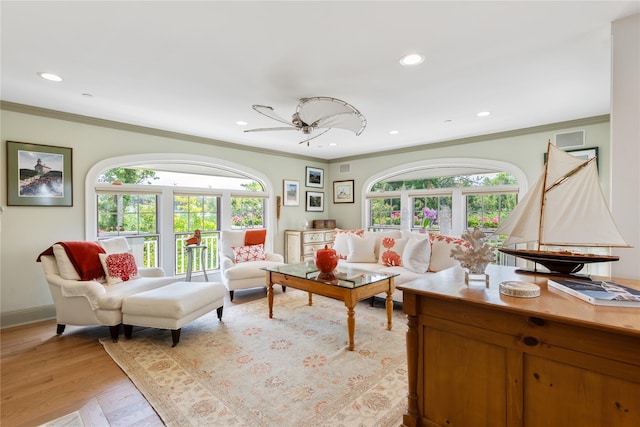 living area with light wood-style floors, plenty of natural light, ornamental molding, and recessed lighting