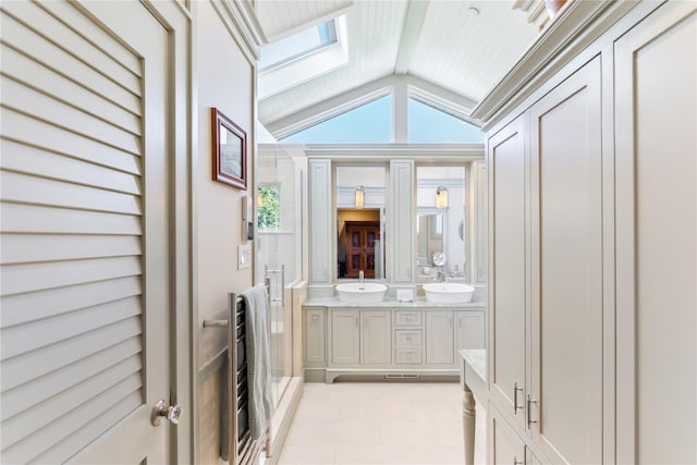 full bath with double vanity, heating unit, vaulted ceiling with skylight, and a sink