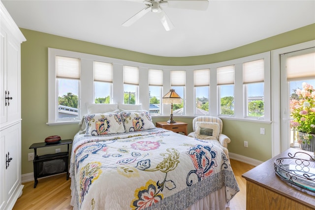 bedroom with light wood-style floors, access to outside, multiple windows, and baseboards