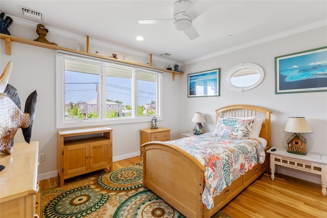 bedroom with light wood-type flooring, visible vents, crown molding, and baseboards