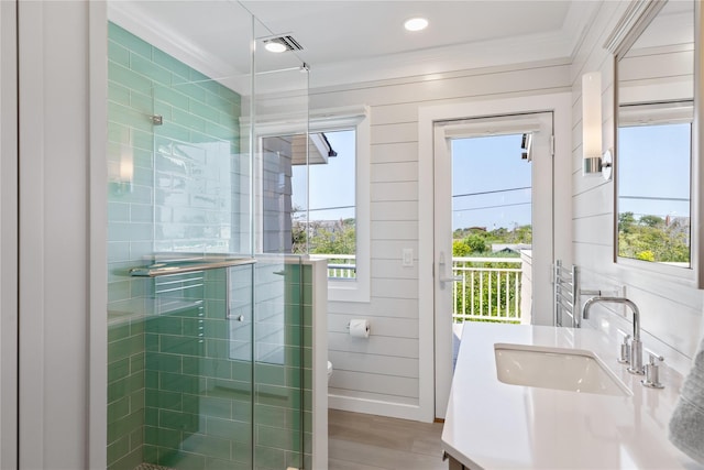 bathroom featuring wood finished floors, visible vents, vanity, a shower stall, and crown molding