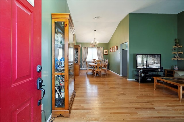 entrance foyer with a chandelier, baseboards, light wood-style flooring, and vaulted ceiling