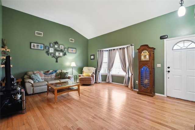 living room with lofted ceiling, baseboards, visible vents, and light wood finished floors