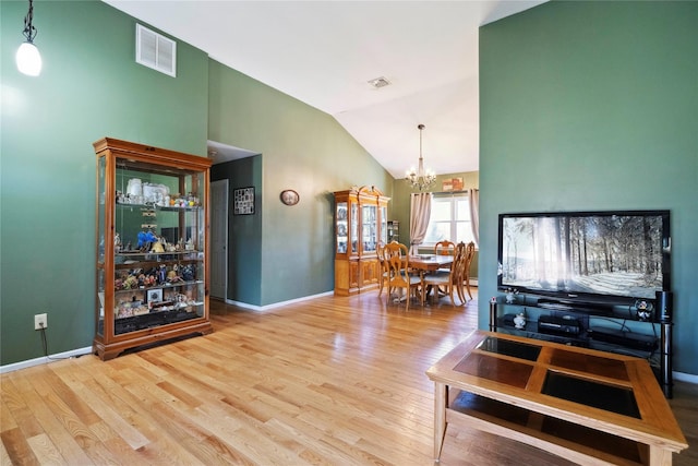 living area with visible vents, lofted ceiling, wood finished floors, and a chandelier