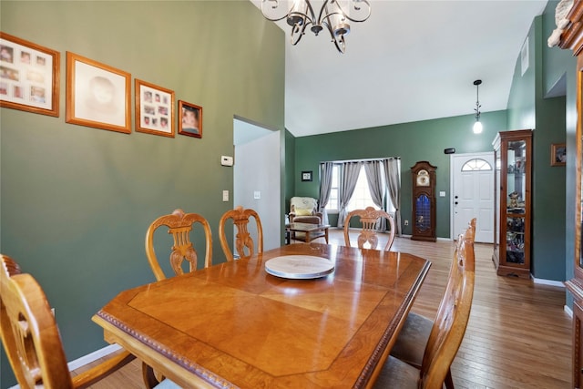 dining area featuring a chandelier, a towering ceiling, baseboards, and wood-type flooring