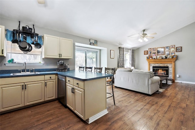 kitchen with dark countertops, a breakfast bar area, dark wood-style floors, and a sink