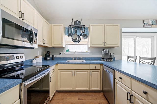 kitchen featuring dark countertops, cream cabinetry, appliances with stainless steel finishes, and a sink