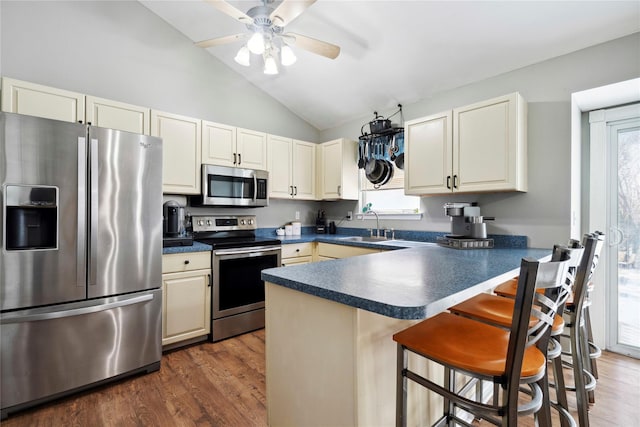 kitchen featuring a breakfast bar, dark countertops, dark wood finished floors, stainless steel appliances, and lofted ceiling