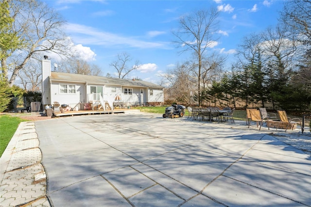 exterior space featuring outdoor dining area, a chimney, and a patio area