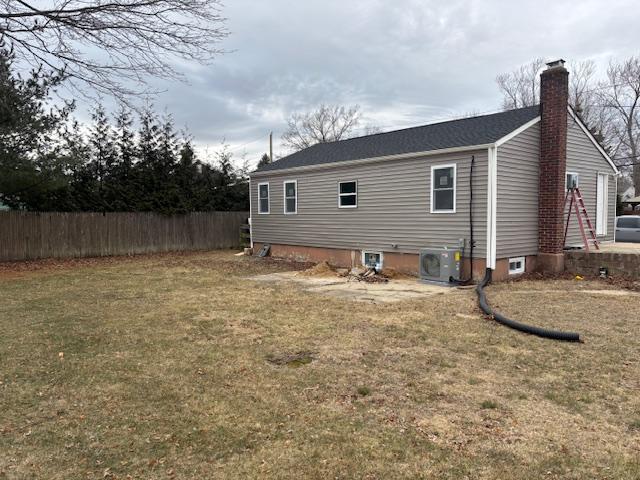 back of house featuring central AC unit, a chimney, fence, and a yard