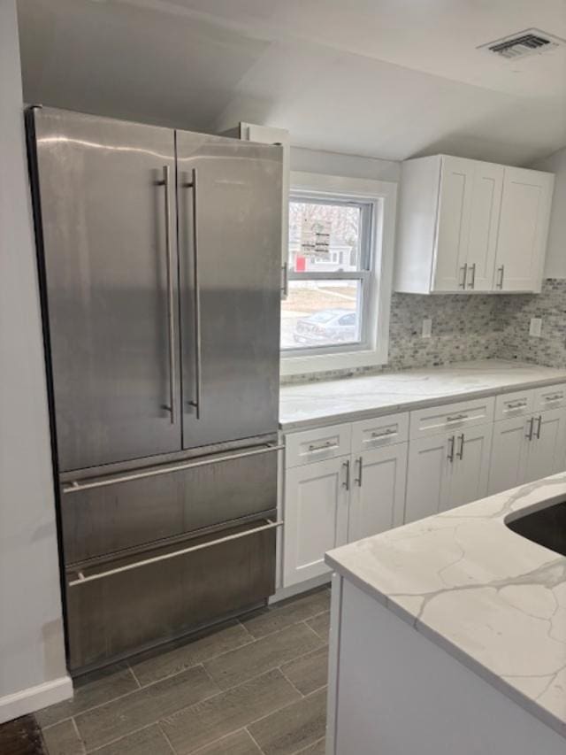 kitchen with white cabinetry, visible vents, stainless steel built in refrigerator, and backsplash