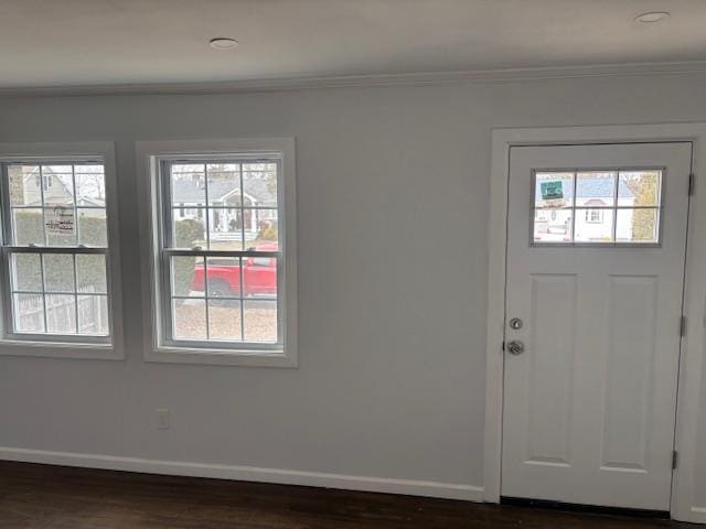 foyer with ornamental molding, dark wood-type flooring, a wealth of natural light, and baseboards