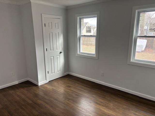 unfurnished bedroom with ornamental molding, baseboards, and dark wood-style floors