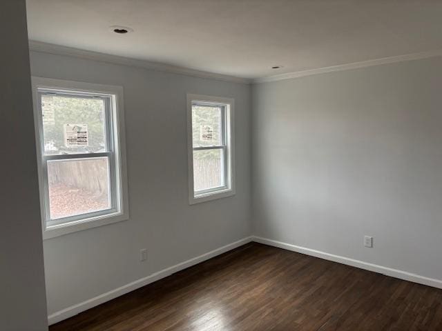 empty room with ornamental molding, dark wood finished floors, and baseboards