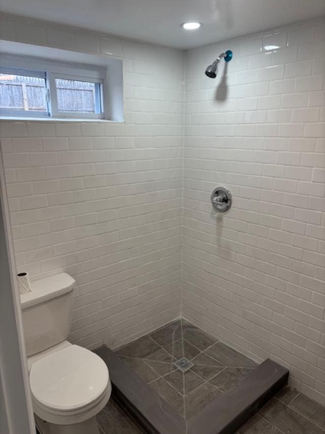 bathroom featuring a tile shower, tile walls, and toilet