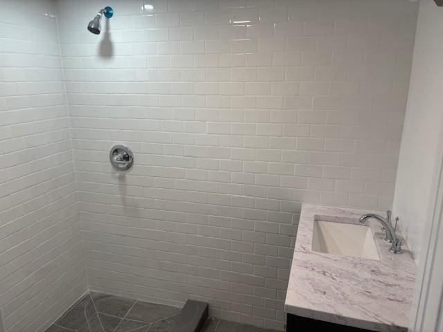 bathroom featuring tiled shower and vanity