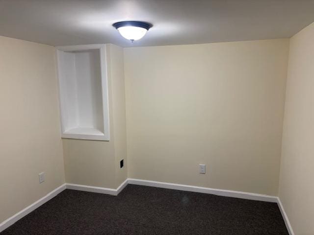 empty room with baseboards and dark carpet