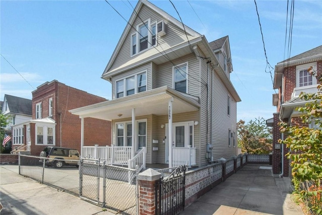 american foursquare style home featuring a fenced front yard, covered porch, and a gate