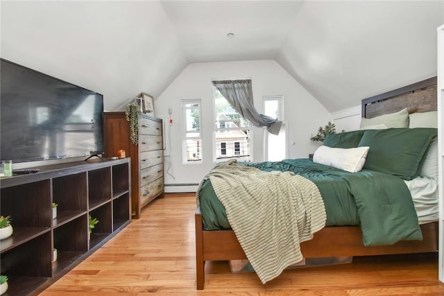 bedroom with light wood-style floors, vaulted ceiling, and baseboard heating