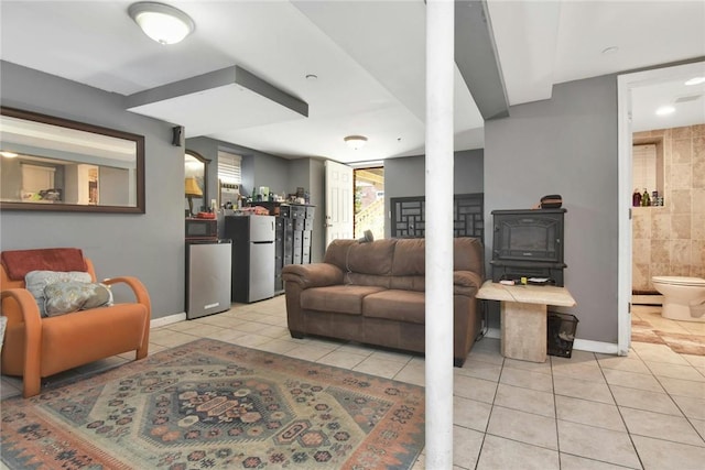 living area with light tile patterned floors, a wood stove, and baseboards