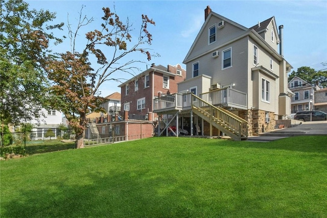 rear view of property featuring a deck, a yard, stairway, and fence