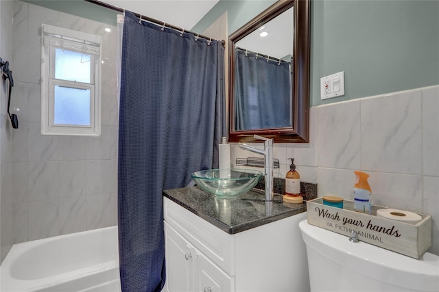 full bathroom with toilet, shower / bath combo, tile walls, and vanity