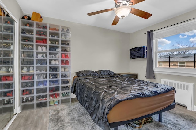 bedroom featuring radiator heating unit, wood finished floors, and a ceiling fan