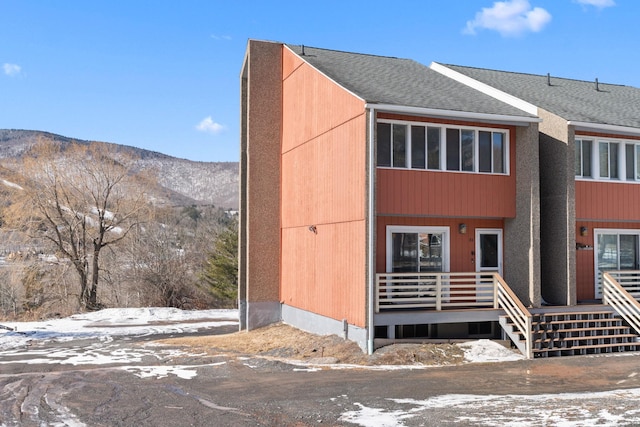 multi unit property with a shingled roof and a mountain view