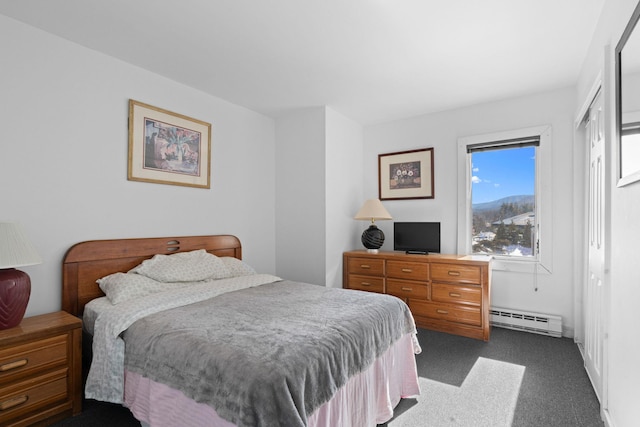 bedroom with a baseboard heating unit and dark carpet