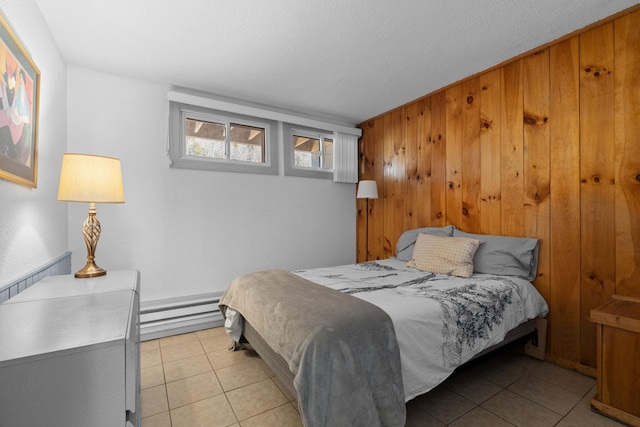 bedroom with a baseboard heating unit, light tile patterned flooring, and wooden walls