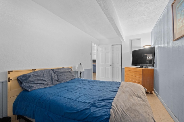 bedroom featuring a textured ceiling, baseboards, and tile patterned floors