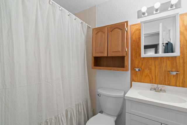 full bathroom with a textured ceiling, a textured wall, toilet, a shower with shower curtain, and vanity