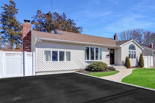 view of front of home featuring a chimney, a gate, fence, and roof with shingles