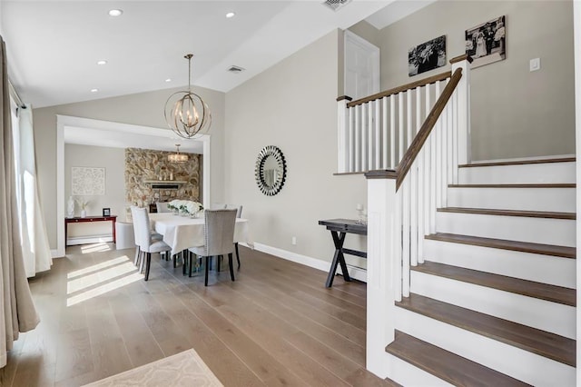 dining area featuring baseboards, visible vents, lofted ceiling, wood finished floors, and stairs