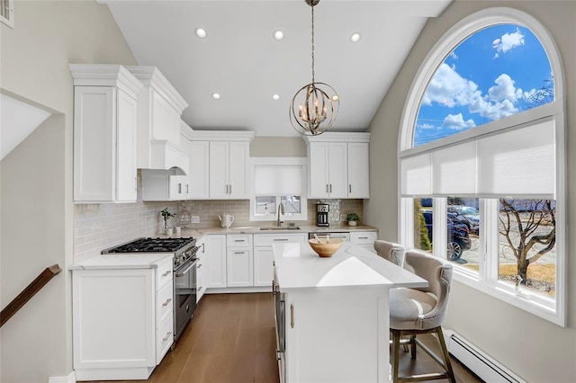 kitchen with white cabinets, high end stainless steel range, light countertops, a baseboard heating unit, and a sink