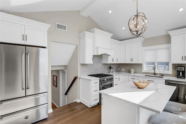 kitchen featuring vaulted ceiling with beams, a sink, visible vents, high quality appliances, and tasteful backsplash